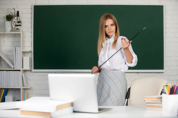 Young teacher with pointer on blackboard with copy space. Portrait of cute attractive young woman student in university or high school college. - Foto, Imagem