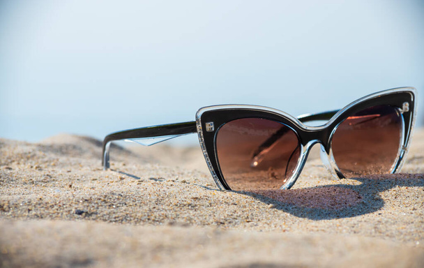 Sunglasses on the beach. Relaxation Vacation Travel - Blue Sea, White Sand, Shining Sun on the Beach. - Fotografie, Obrázek