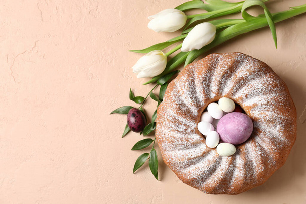 Tasty Easter cake, tulip flowers and eggs on beige background - Photo, Image