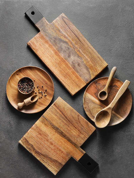 Wooden cutting boards, plates and spoons on black background - Photo, Image