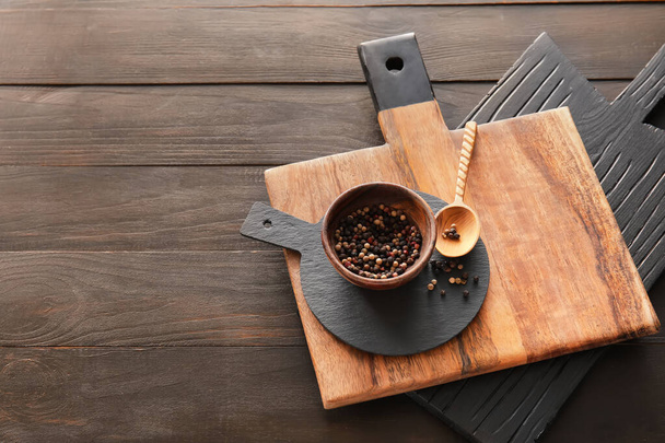 Cutting boards and bowl with peppercorn on dark wooden background - Photo, Image
