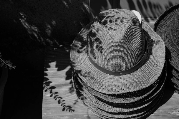 Montón de sombreros clásicos para hombres de paja. Comercio callejero. Turismo de compras en Francia. Sol brillante en duras sombras. Foto en blanco y negro. - Foto, imagen
