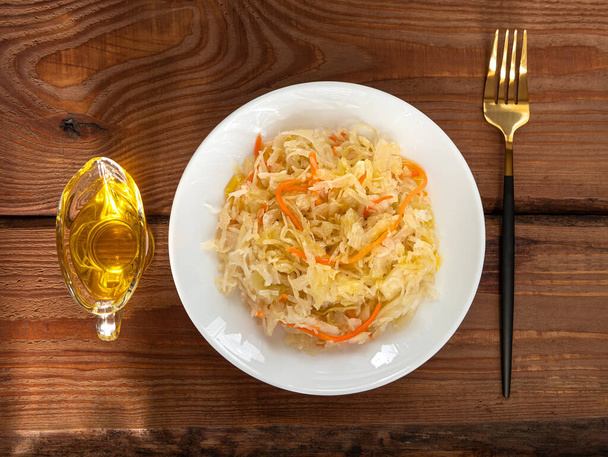 Τρώγοντας ξινολάχανο με φυτικά έλαια. Εθνικό ευρωπαϊκό πιάτο Καρότο τουρσί λάχανο Σπιτικό ζυμωμένο από βακτήρια γαλακτικού οξέος Άλμη Lactobacillus. Υγιεινό τοπικό φαγητό ξινή γεύση Βιταμίνη C Winter menu - Φωτογραφία, εικόνα