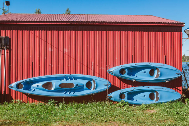 Tres kayaks y paletas cuelgan de la pared para secarse. Almacenamiento de equipos de deportes acuáticos y turísticos - Foto, imagen