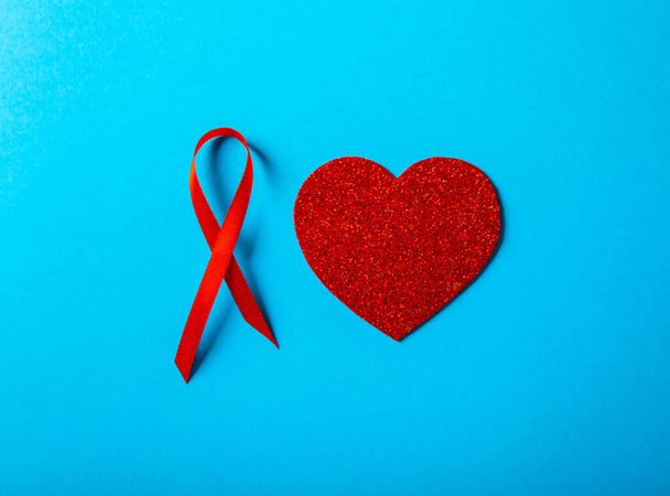 Mavi arka planda kırmızı kalpli kırmızı kurdele, HIV, AIDS ve kanserle mücadelenin sembolü. yoksul konsepte yardım - Fotoğraf, Görsel
