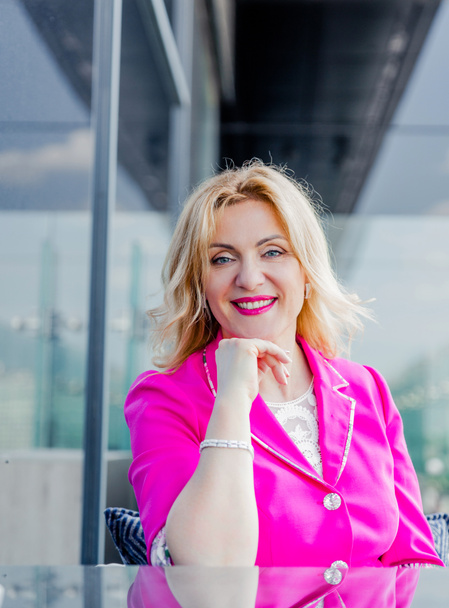 Successful woman entrepreneur in a magenta jacket posing on the terrace of a cafe in a business center. Business woman representation concept - Фото, изображение