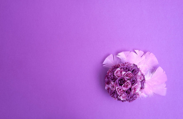 Purple bouquet of artificial roses on pink feathers on a purple violet background. Text space. Celebrations, weddings, Valentine's Day. Minimal style. Top view. Flat lay. - Fotografie, Obrázek