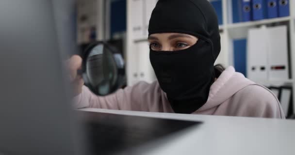 Man in balaclava looking at laptop screen with magnifying glass 4k movie - Footage, Video
