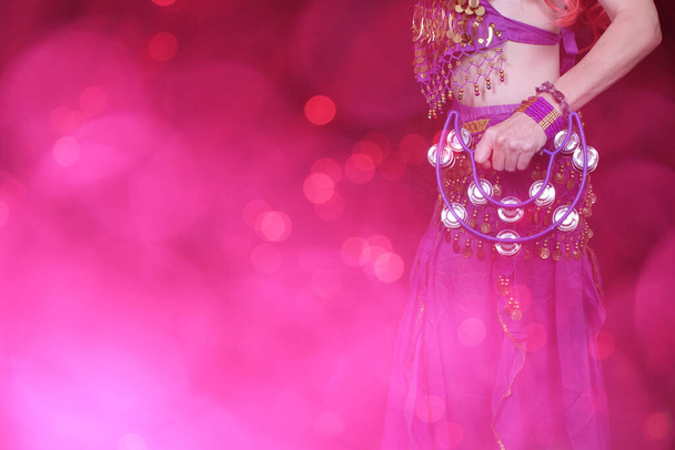 Göbek Dansçısı mor dans kostümü giyiyor. Renkli bokeh ile yakın plan. - Fotoğraf, Görsel