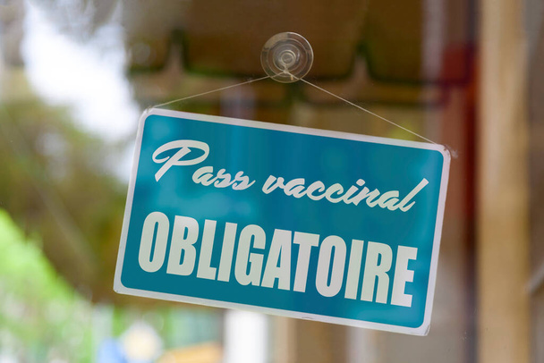 Lähikuva punaisesta merkistä myymälän ikkunassa, jossa on viesti ranskaksi - Passin mukainen rokotusvelvollisuus - merkitys englanniksi - Pakollinen rokotuskortti -. - Valokuva, kuva