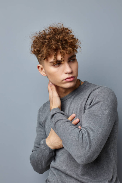 handsome guy in a gray sweatshirt fashion studio Gray background - Фото, изображение