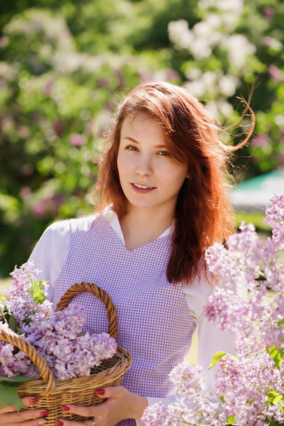 Jovem bela mulher ruiva em um vestido vintage em um jardim com floração lilás - Foto, Imagem