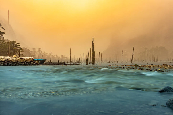 lago cubierto de niebla y troncos de árboles secos por la mañana de la imagen de ángulo plano se toma en el lago madhuri tawang arunachal pradesh. - Foto, Imagen