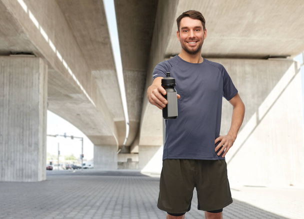 smiling man in sports clothes with bottle - Фото, зображення
