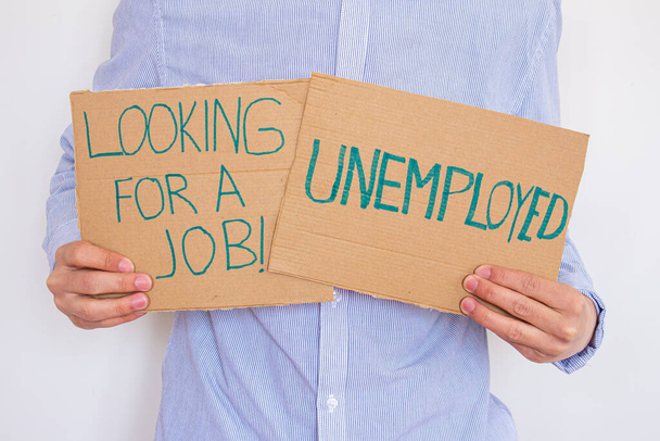 Hombre desempleado sosteniendo un letrero con inscripción en busca de trabajo. Concepto de perder trabajo y buscar uno nuevo. Está teniendo problemas financieros.. - Foto, imagen