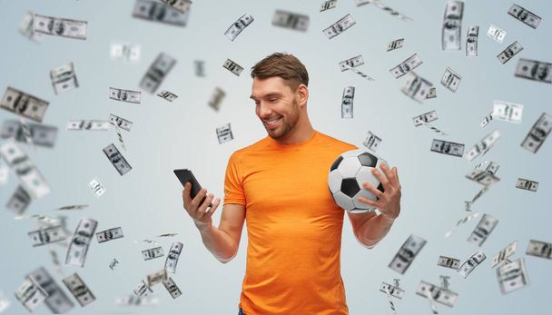 чоловік зі смартфоном і футбольним м'ячем над грошима
 - Фото, зображення