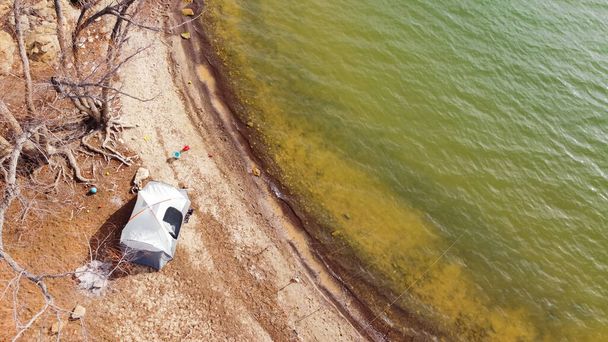 Vista aérea grande barraca familiar e brinquedos de areia para crianças perto da costa rochosa ao longo do Lago Grapevine, Texas, América. Lakeside acampamento com fogueira apagada no inverno em trilha de pesca natural - Foto, Imagem