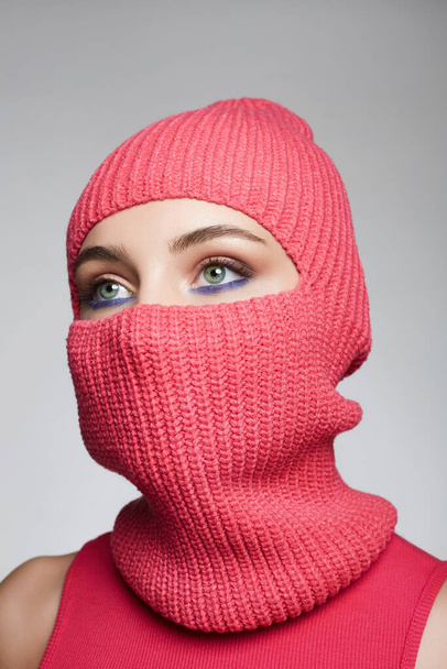 beautiful eyes of girl in red balaclava. New Hat style. Trendy Mask on pretty woman - Фото, изображение