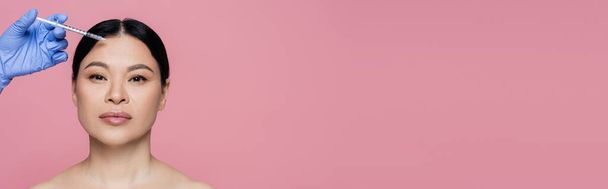 Kosmetologi tilalla ruisku lähellä kasvoja aasialainen nainen paljain hartioin eristetty vaaleanpunainen, banneri  - Valokuva, kuva