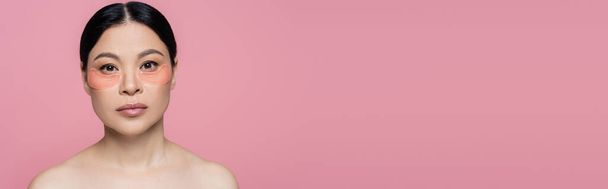 Asian woman with eye patches looking at camera isolated on pink, banner  - Foto, afbeelding