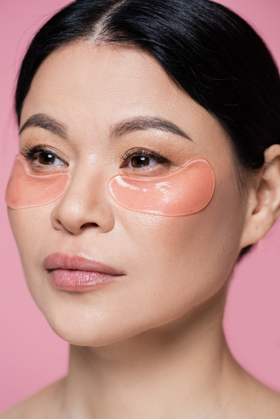 Portrait of asian woman with eye patches looking away isolated on pink  - Foto, Imagem
