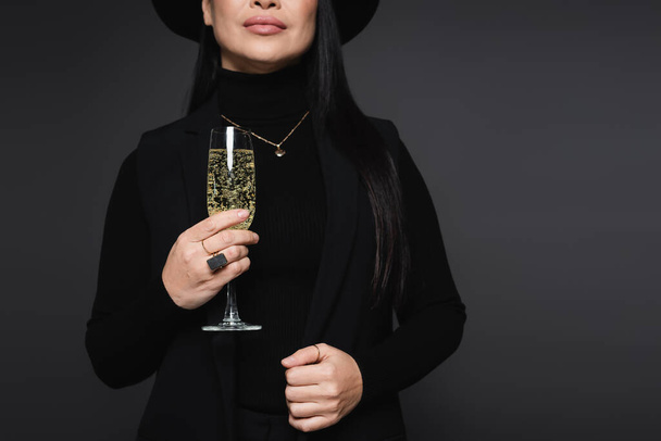 Обрезанный вид стильной женщины, держащей бокал шампанского изолированный на темно-серой - Фото, изображение