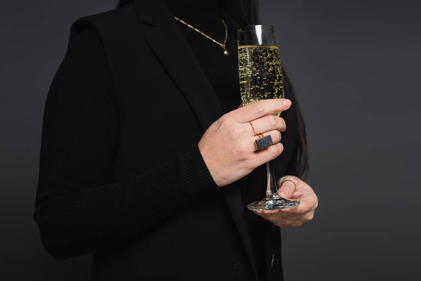 Cropped view of woman in jacket holding glass of champagne isolated on dark grey - Fotoğraf, Görsel