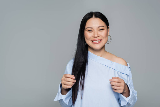 Happy asian model in blouse looking at camera isolated on grey  - Photo, Image