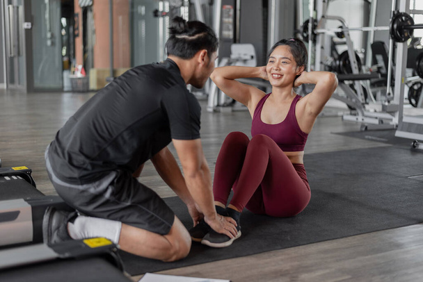 Asyalı kadın spor salonunda kişisel antrenörle egzersiz yapıyor. Asyalı sağlıklı kadın kişisel koçuyla fitnelerde karın kası egzersizi yapıyor.. - Fotoğraf, Görsel