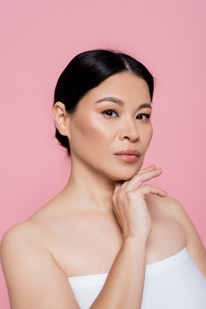 Asian woman in white top posing and looking at camera isolated on pink  - Fotoğraf, Görsel