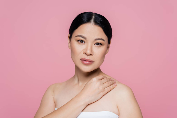 Asian woman in top touching shoulder isolated on pink  - Φωτογραφία, εικόνα