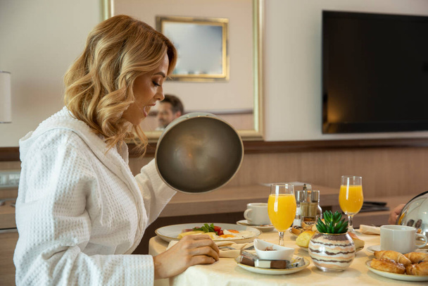 Attractive woman in bathrobe having breakfast in hotel room - Foto, immagini