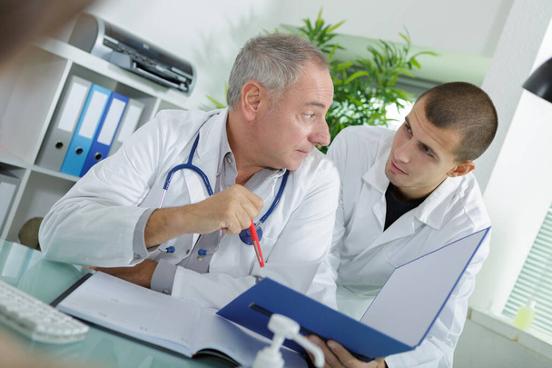 doctor checking medical records with assistant - 写真・画像