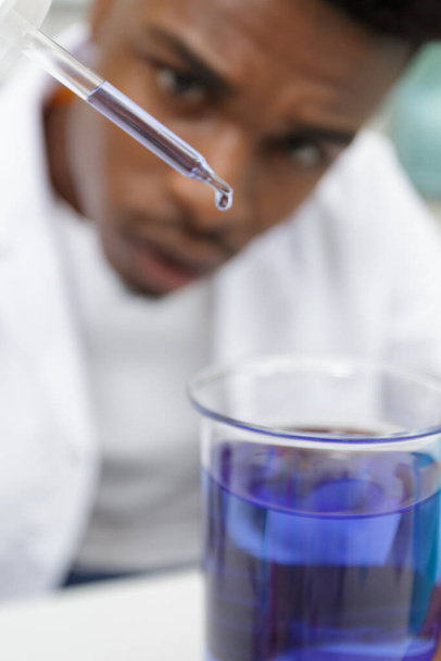 young man scientist using auto-pipette with flask in medical laboratory - Fotografie, Obrázek