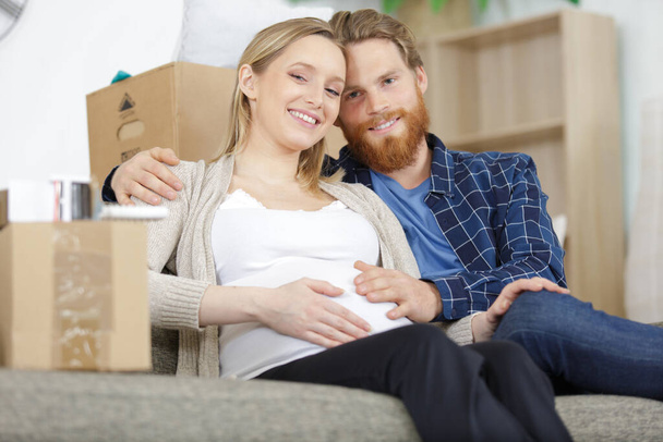 pregnant couple with boxes on sofa - Photo, image