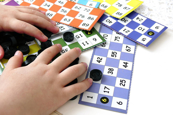 dziecko bawi się kawałkami bingo, zbliżenie rękę trzyma kawałki bingo, - Zdjęcie, obraz