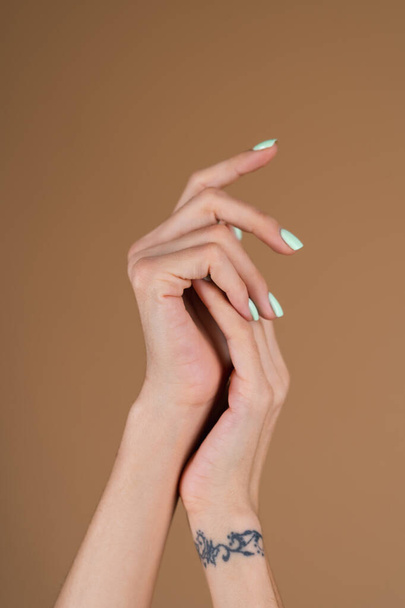 Mani femminili graziose con dita lunghe sottili e manicure turchese alla menta su uno sfondo beige - Foto, immagini