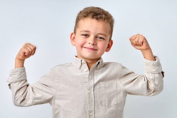Handsome confident child boy in casual shirt smiling happily and raising clenched fists - Fotoğraf, Görsel