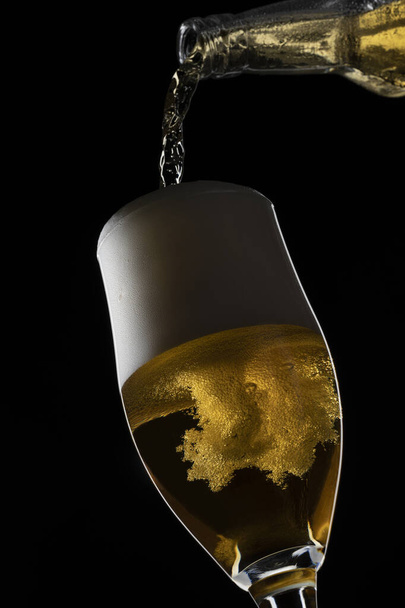 a beer pouring in a glass on a black background. - Zdjęcie, obraz