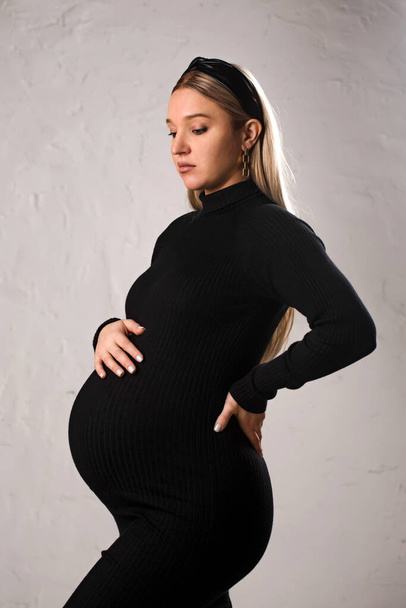 Portrait of a young beautiful pregnant woman in a black dress - Foto, afbeelding