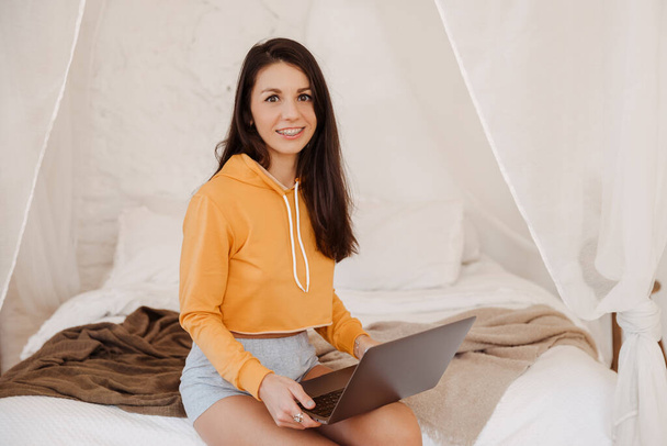 portrait of young freelancer woman using laptop and working at bedroom - Fotografie, Obrázek