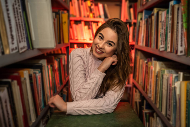Üniversite kütüphanesinde kitap arayan genç bir kız öğrenci. - Fotoğraf, Görsel