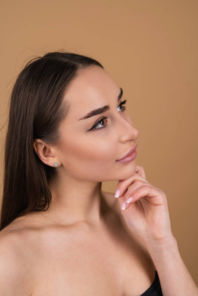 Sluiten schoonheid portret van een topless vrouw met perfecte huid en natuurlijke make-up, glanzende lippen, op een beige achtergrond - Foto, afbeelding