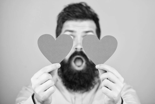 Guy attractive with beard and mustache in romantic mood. Feeling love. Dating and relations concept. Happy in love. Love is amazing. Man bearded hipster with heart valentine card. Celebrate love - 写真・画像