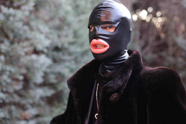primer plano retrato de hombre en bdsm esclavo máscara de látex y abrigo de piel al aire libre - Foto, imagen