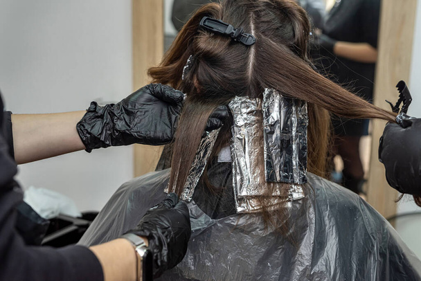 az elit szépségszalonban csodálatos hajfestéket készítenek egy kifinomult hölgynek sötét hajjal. Női haj koncepció. Szépségszolgáltatási koncepció - Fotó, kép
