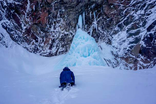 The guy climbs in the snow to the Vilyuchinsky waterfall in winter - Photo, Image