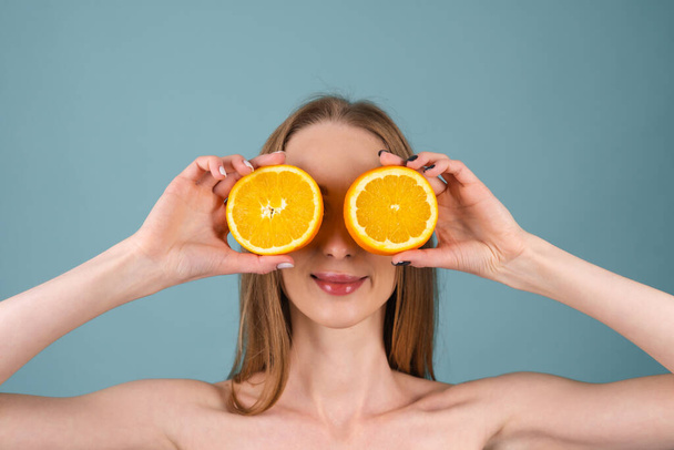 Detailní portrét ženy nahoře bez s perfektní pletí a přirozeným make-upem, plné nahé rty, držící čerstvý citrusový vitamin C oranžový - Fotografie, Obrázek