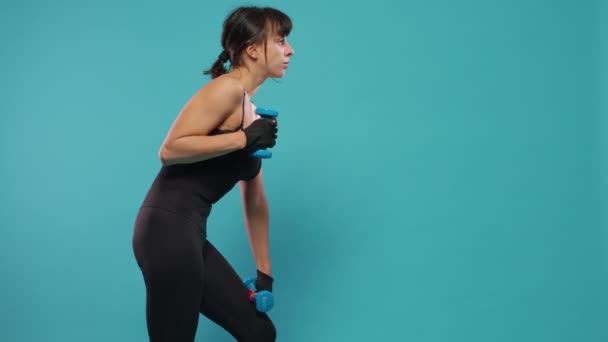 Атлетичная женщина использует гантели для тренировок в студии - Кадры, видео