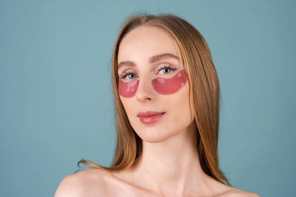 Schönheitsporträt einer Frau ohne Oberteil mit perfekter Haut und natürlichem Make-up, rosafarbenen Flecken unter den Augen, um die Haut zu befeuchten und Schwellungen im Gesicht zu lindern - Foto, Bild